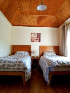 two beds in a room with wooden ceilings at Nanny Quinn's Apartment in Killucan