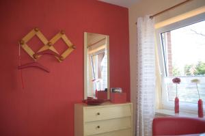 una camera da letto con pareti rosse, specchio e cassettiera di Ferienwohnung Grensemann a Schneverdingen