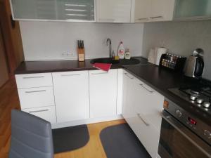 a kitchen with white cabinets and a black counter top at Justinos Apartamentai Panevėžyje in Panevėžys
