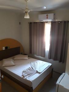 a bedroom with a bed and a window with a white bedspread at HOTEL LAREIRA in São José dos Campos
