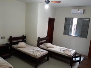 2 camas individuales en una habitación con ventana en HOTEL LAREIRA, en São José dos Campos
