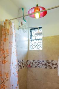 a bathroom with a shower curtain and a window at Serene Homes in Mombasa