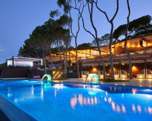 a swimming pool in front of a building at night at Alàbriga Hotel & Home Suites GL in S'Agaro