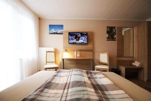 - une chambre avec un lit et une télévision murale dans l'établissement Pension Yak und Yeti, à Bad Honnef