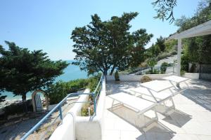 Un balcón con sillas blancas y vistas al océano. en case vacanza montesaraceno, en Mattinata