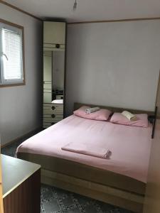 una camera da letto con un letto con lenzuola rosa e uno specchio di Ada Bojana Apartmani a Ulcinj