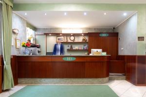 a man standing at the reception desk of a pharmacy at Hotel Dorè in Milan