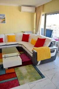 een woonkamer met een witte bank en kleurrijke kussens bij Rue Roland Garros in Fréjus