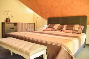 Un dormitorio con una cama grande y un banco en Villa Quality Wellness, en Dozmat