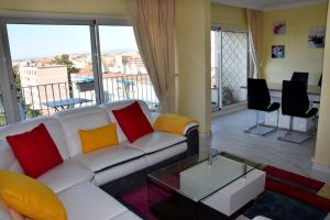 a living room with a white couch with colorful pillows at Rue Roland Garros in Fréjus