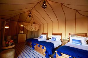 a bedroom with two beds in a tent at Sahara Luxury Camp in Merzouga