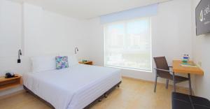 um quarto com uma cama, uma secretária e uma janela em Del Mar Hotel em Santa Marta