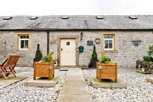 a stone cottage with two chairs and a white door at Juniper Cottage in Bakewell