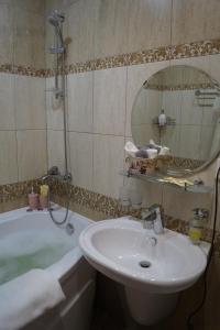 a bathroom with a sink and a tub and a mirror at Schastie na Rubinsteina - Apartments in Saint Petersburg