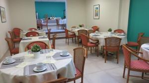 un comedor con mesas y sillas con manteles blancos en Résidence Mer & Golf Eugénie, en Biarritz