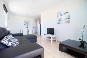 a living room with a couch and a tv at Residencial Arena del Sol 6 by Olax Rentals in Puerto de Santiago
