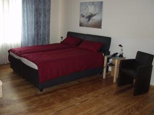 a bedroom with a bed with a red comforter and a chair at Exklusive Gästezimmer Landau in Landau in der Pfalz