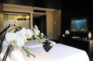 Cette chambre d'hôtel comprend un lit orné de fleurs blanches. dans l'établissement Evidencia Belverde Hotel, à Amora