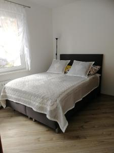 a bedroom with a bed with white sheets and a window at Apartament Klimek in Białka Tatrzańska