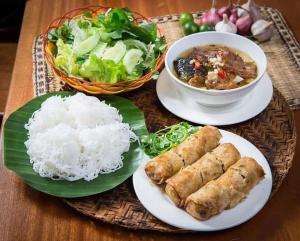 a table with plates of food and a bowl of rice at Tam Coc Tuan Minh Homestay in Ninh Binh