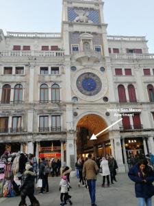 un edificio con una torre de reloj con gente caminando alrededor en Venice San Marco Apartment, en Venecia