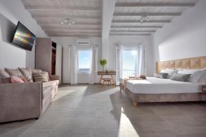 a white bedroom with a large bed and a couch at Amelie Suites in Agios Stefanos