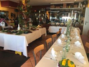 een rij tafels in een restaurant met witte tafelkleden bij Hotel Bacchus Wine & Bites in Meersburg