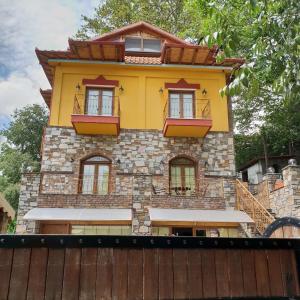 a yellow building with windows and a wooden fence at Santa Marina Guesthouse in Kato Loutraki