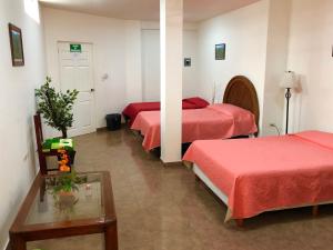 a hotel room with three beds and a table at Hostal Cristo Rey in Ciudad Valles