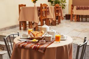einen Tisch mit einem Teller Brot und Orangensaft in der Unterkunft Hostal Danna Inn in Cusco