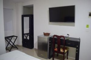 a bedroom with a desk and a television on a wall at Hotel Intersuites in Barranquilla