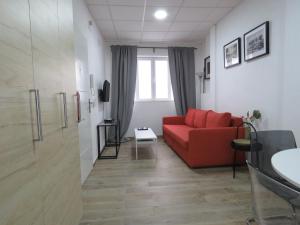 a living room with a red couch and a window at Living Sevilla Apartments H&eacute;rcules in Seville