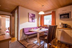 ein Wohnzimmer mit einem Tisch und einem lila Sofa in der Unterkunft Appartements Enzian in Finkenberg