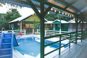 a swimming pool with a wooden deck and a pergola at Caboclos House Eco-Lodge in Manacapuru