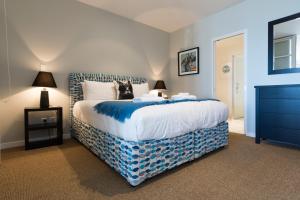 Un dormitorio con una cama grande con sábanas azules y blancas. en Latitude Waterfront Apartment, en Nelson