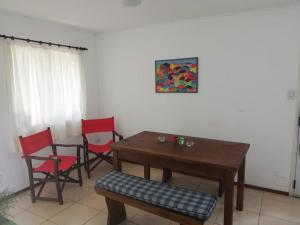 a dining room with a wooden table and red chairs at la casita de colonia 2 in Colonia del Sacramento +16 photos