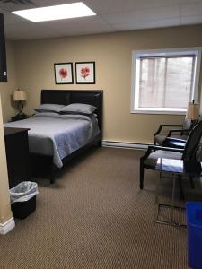 1 dormitorio con cama, ventana y silla en Riverview Suites, en Clarenville
