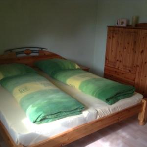 ein Holzbett mit grünen Kissen darauf in der Unterkunft Ferienwohnungen am Schwanenteich in Mühlhausen
