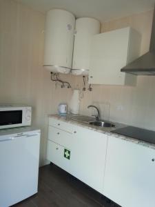 a kitchen with white cabinets and a sink and a microwave at JJ Marto in Fátima