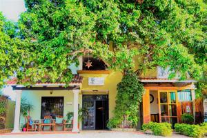 a yellow house with a tree in front of it at El Roble Hotel in Bacalar