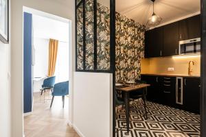 eine Küche mit schwarzen Schränken und einem Tisch im Zimmer in der Unterkunft MM Suites Marlot in Reims