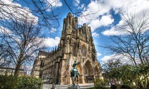 a statue of a man on a horse in front of a building at MM Suites Marlot in Reims