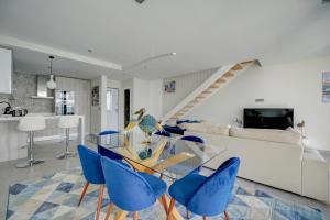 uma sala de jantar com uma mesa de vidro e cadeiras azuis em Arade Riverside Modern Apartment em Estômbar