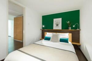 a bedroom with a large bed with a green headboard at Budapest Downtown Museum Apartments in Budapest