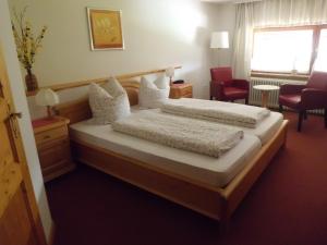 a bedroom with two beds and a chair and a window at Pension Wiesengrund in Schluchsee