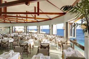 um restaurante com mesas e cadeiras com o oceano ao fundo em The Reefs Resort and Club em Southampton