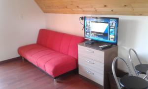 Sofá rojo con TV en la parte superior de una cómoda en Cabaña Los Llanitos Guatavita en Guatavita