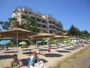 a group of people sitting on a beach with umbrellas at Akra Apartments in Chernomorets