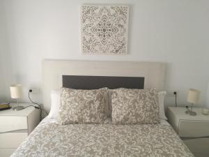 a white bedroom with a bed with two tables and two lamps at Piso Con Terraza y Vistas Espectaculares in Carmona +30 photos