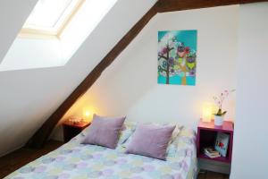 a bedroom with a bed with purple pillows in a attic at Le Coquillage in Granville